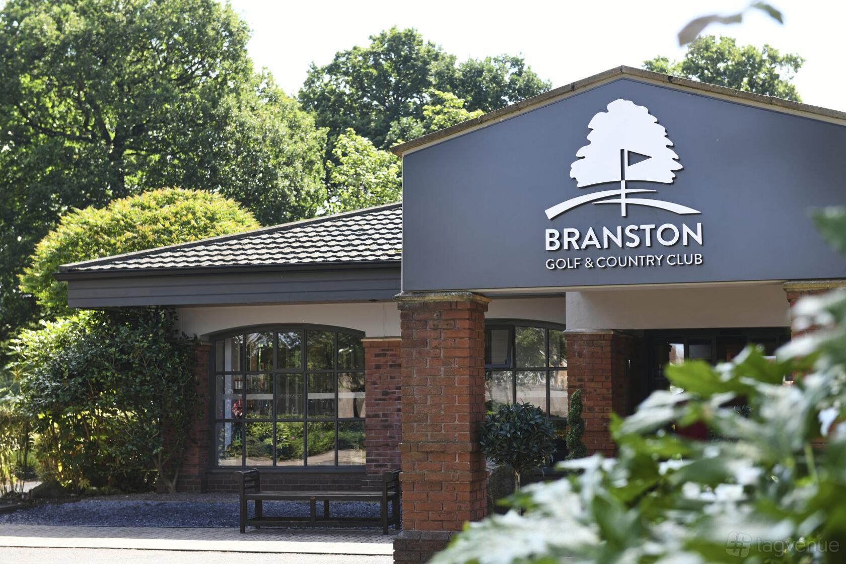 An event venue with a covered entrance, brick columns, and large windows at Branston Golf & Country Club.