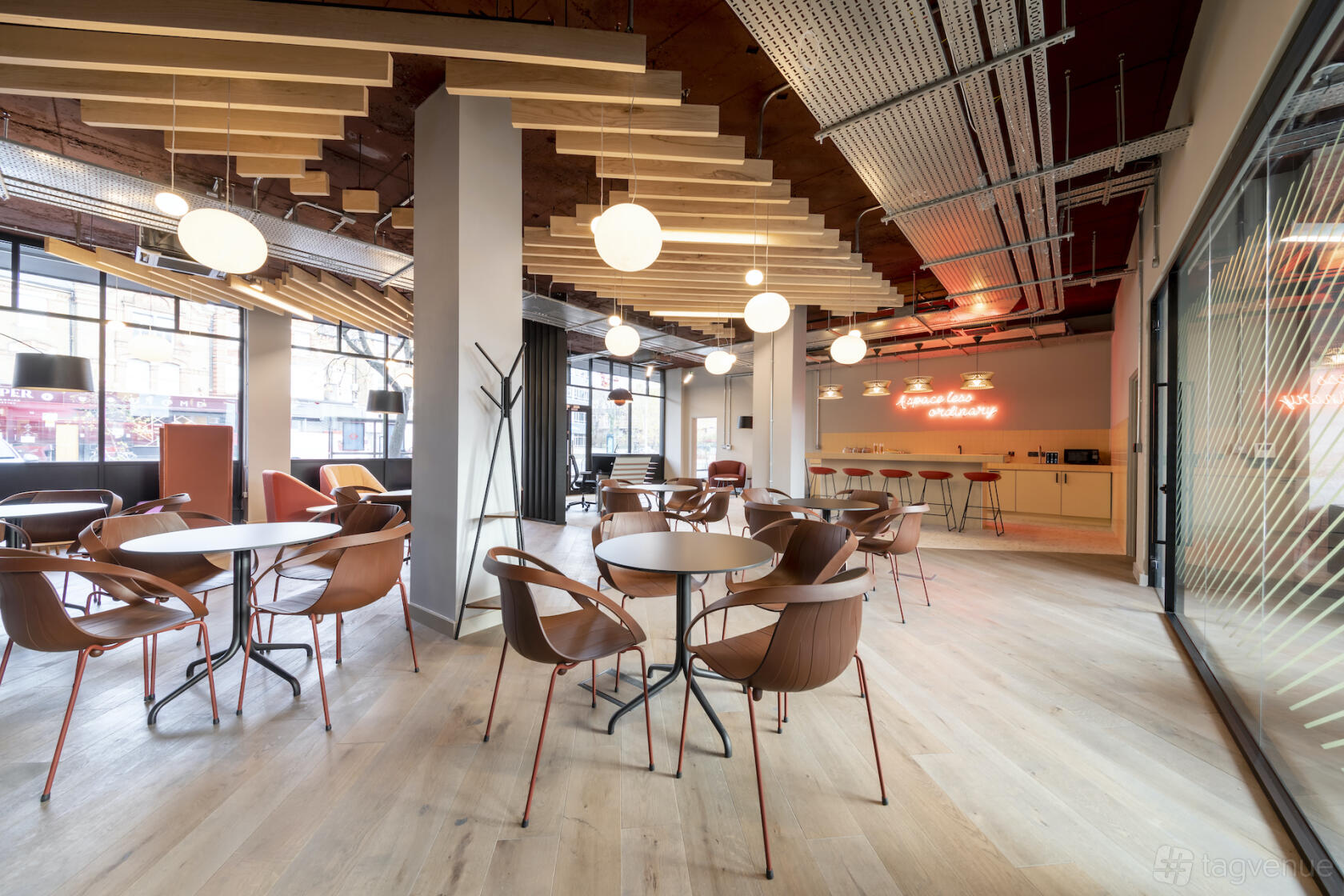 An event space with circular tables, brown chairs, globe pendant lights, and large windows at Saunders House.