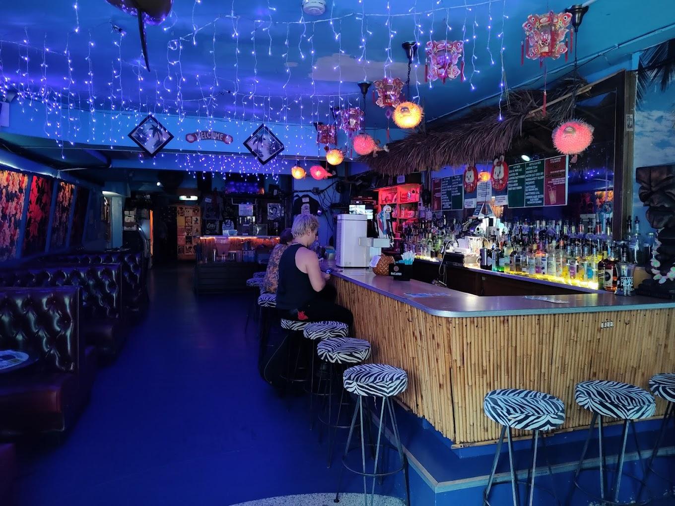 A tiki bar with bamboo paneling, hanging lanterns, string lights, and zebra print stools at Otto's Shrunken Head.