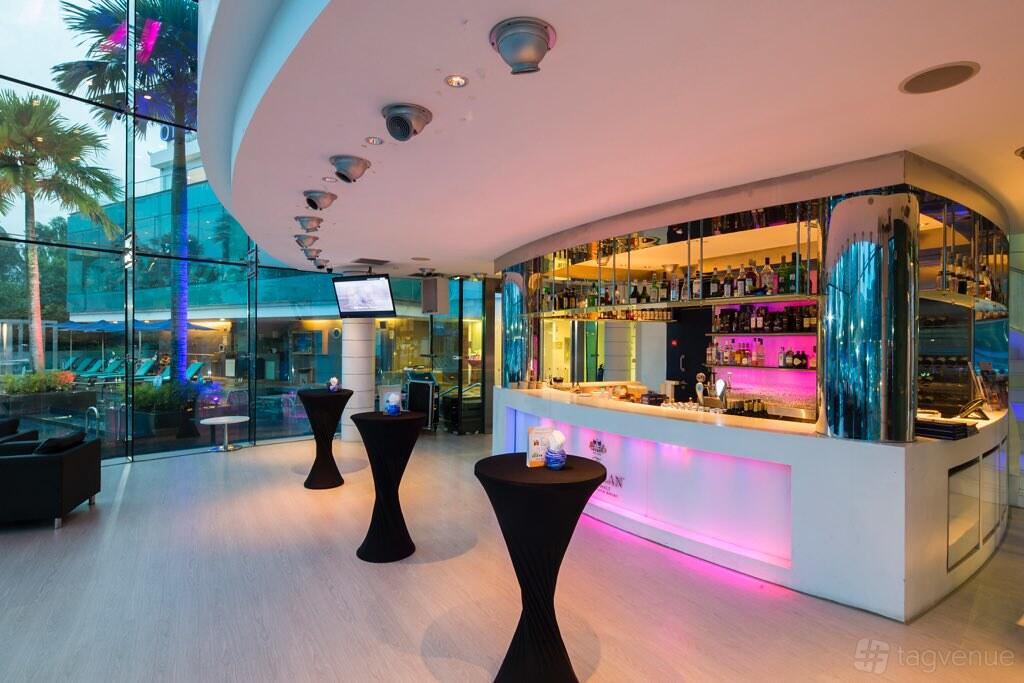 A bar in a hotel with floor-to-ceiling glass windows, modern bar counter with colorful underlighting at ONE°15 Marina Sentosa Cove.