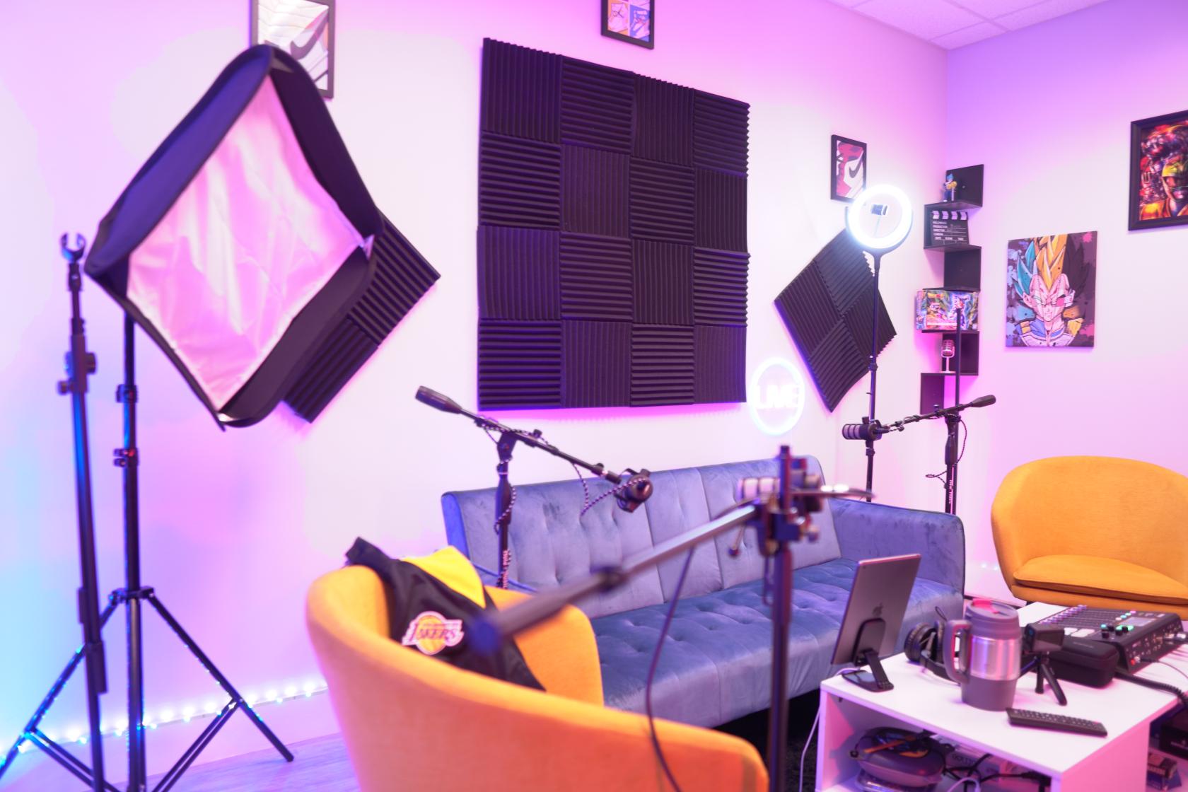 A film studio with acoustic foam panels, recording microphones, and colorful LED lighting at The Pod Pad.