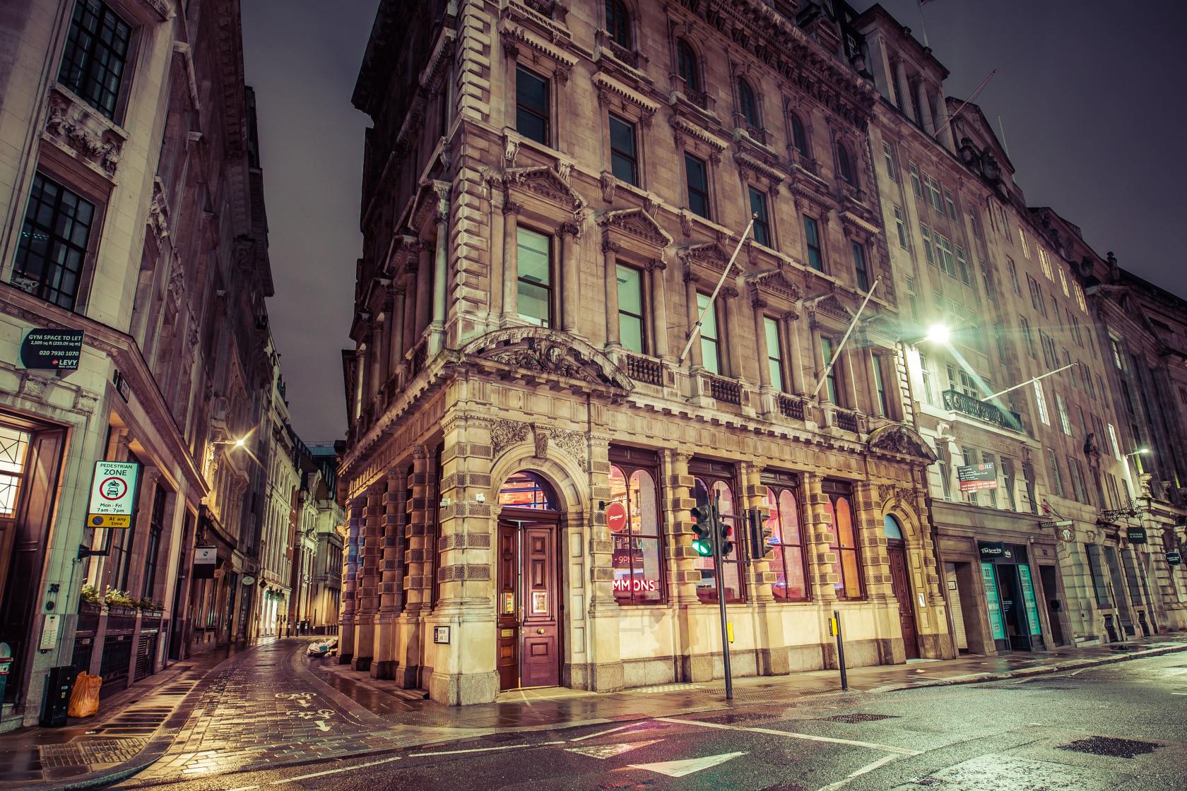 A pub with arched windows and warm interior lighting in a historic stone building at Simmons | Bank.