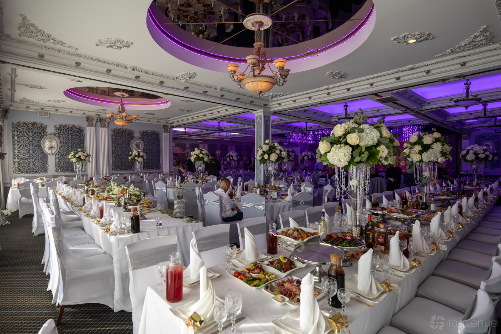 A restaurant with ornate ceilings, purple accent lighting, and banquet tables set for an event at Emperor Restaurant.