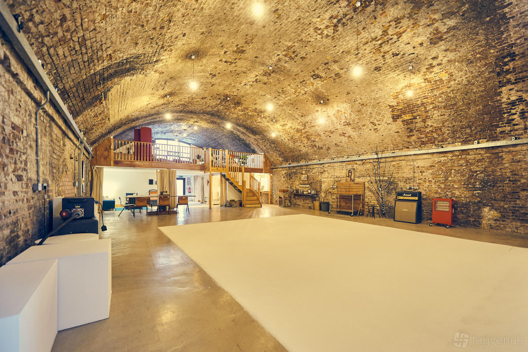 An event venue with exposed brick vaulted ceilings, open floor space, and a mezzanine at Motel Studios.