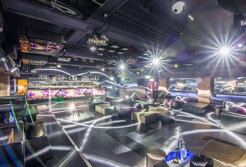 An event space in a bar with illuminated dance floor, lounge seating, and mirrored bar at Sway.