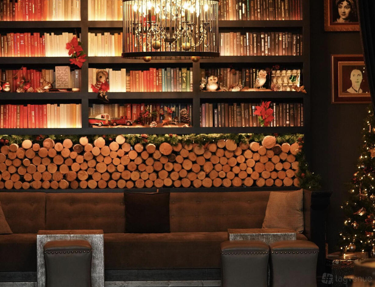 A cocktail bar with bookshelves, festive decorations, and a stacked log feature wall at Novela.