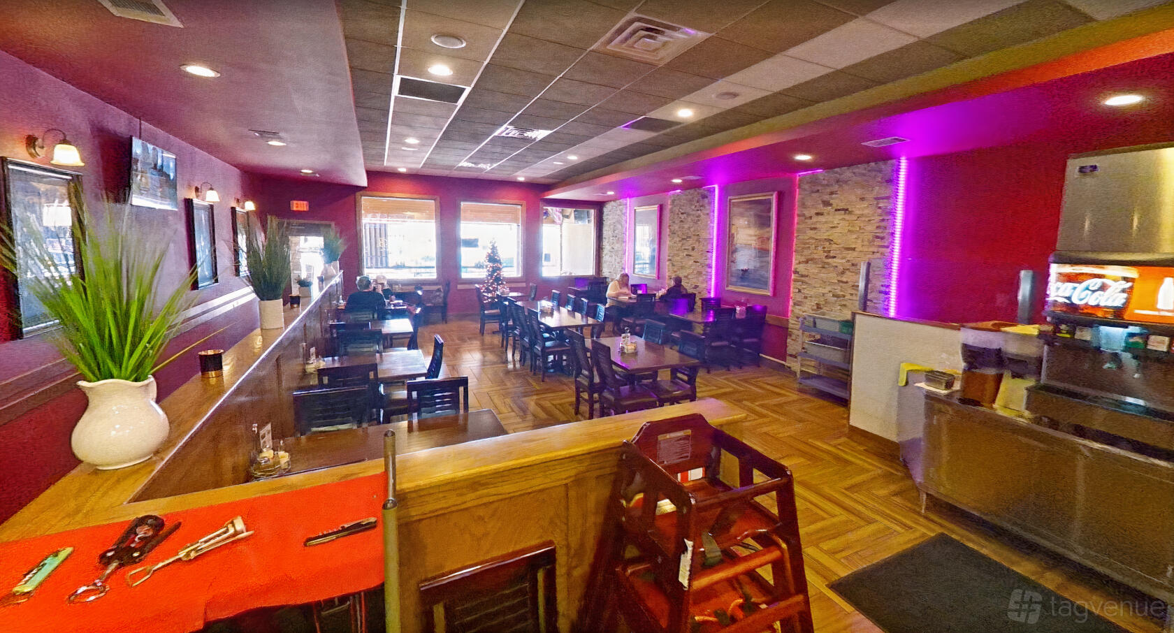 A restaurant with wood flooring, purple accent lighting, brick feature walls, and dining tables at Di Rosani's.
