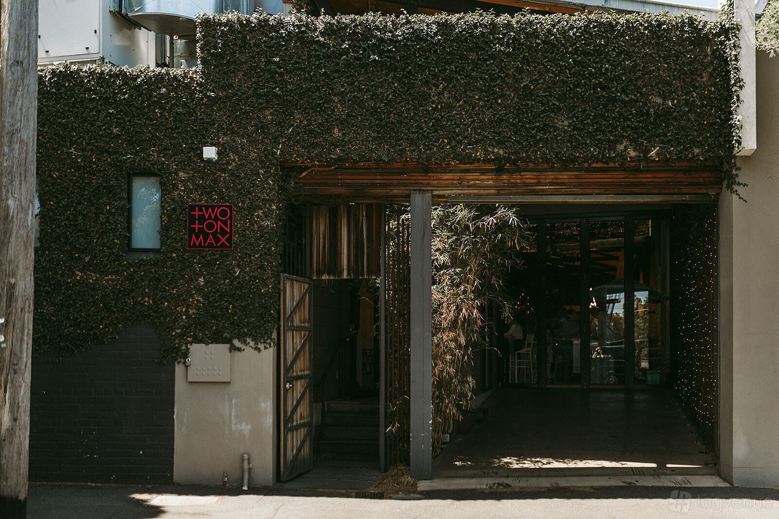 A terrace at an event venue with ivy-covered walls, bamboo plants, and an open entry at Two Ton Max.