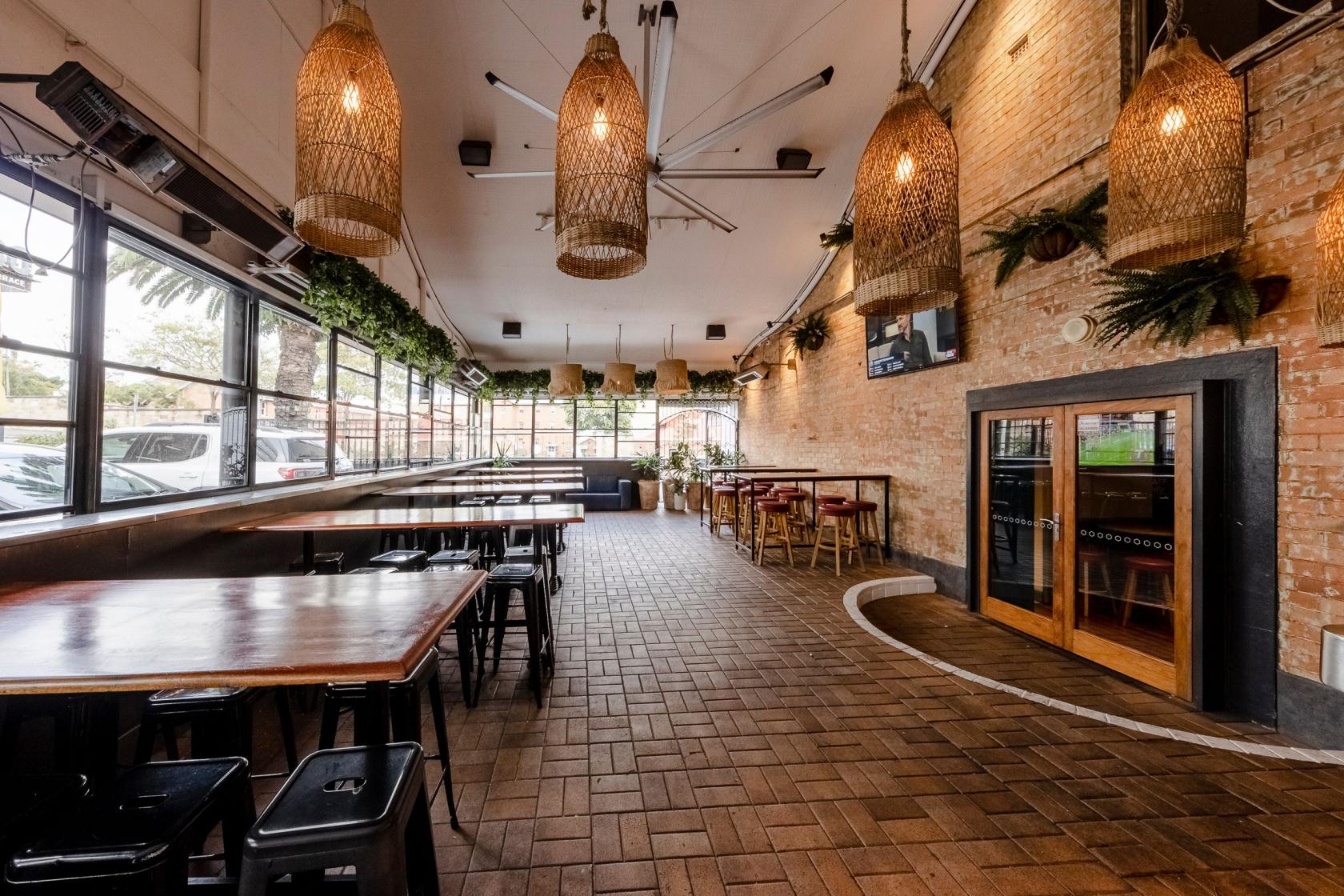 A function room with exposed brick walls, basket pendant lights, and large windows at The Lord Alfred.