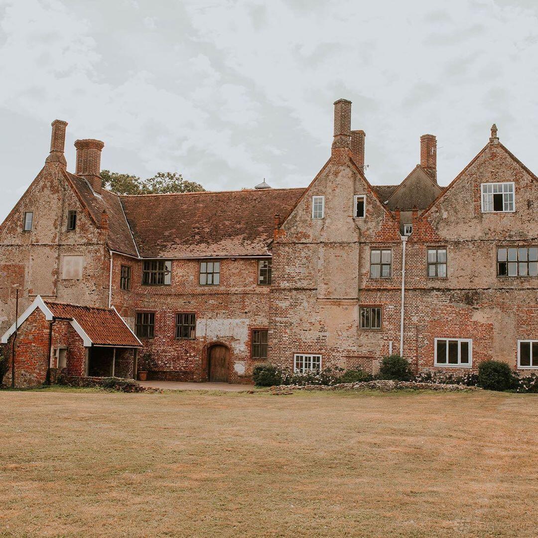 A country house hall with red brick exterior, pitched roofs, and tall chimneys at Bruisyard Country Estate.