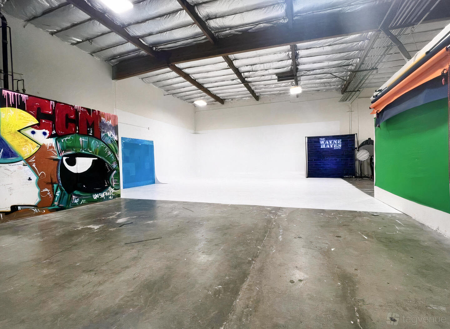 A photo studio with a large white cyclorama wall, polished concrete floors, and graffiti art at CCM Studios.