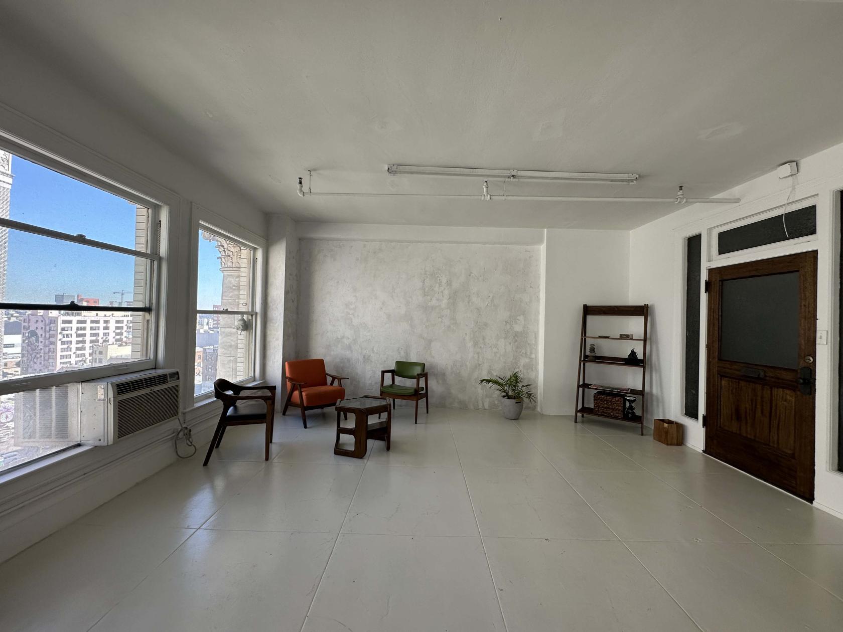 A photo studio with large windows, white floors, minimalist furniture, and textured walls at magphotostudio.