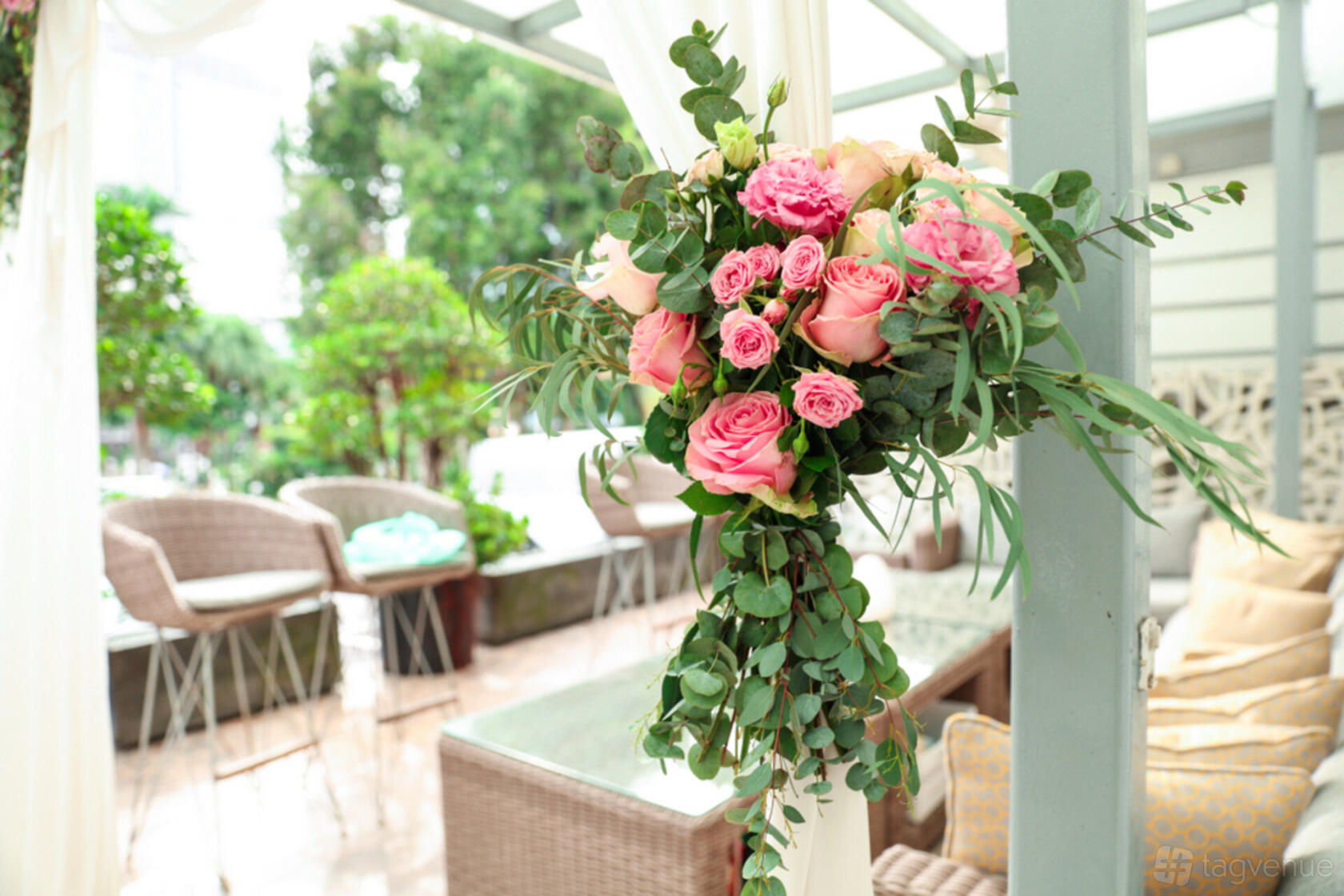 A restaurant with a floral arrangement of pink roses and greenery on a covered patio at Alma by Juan Amador.