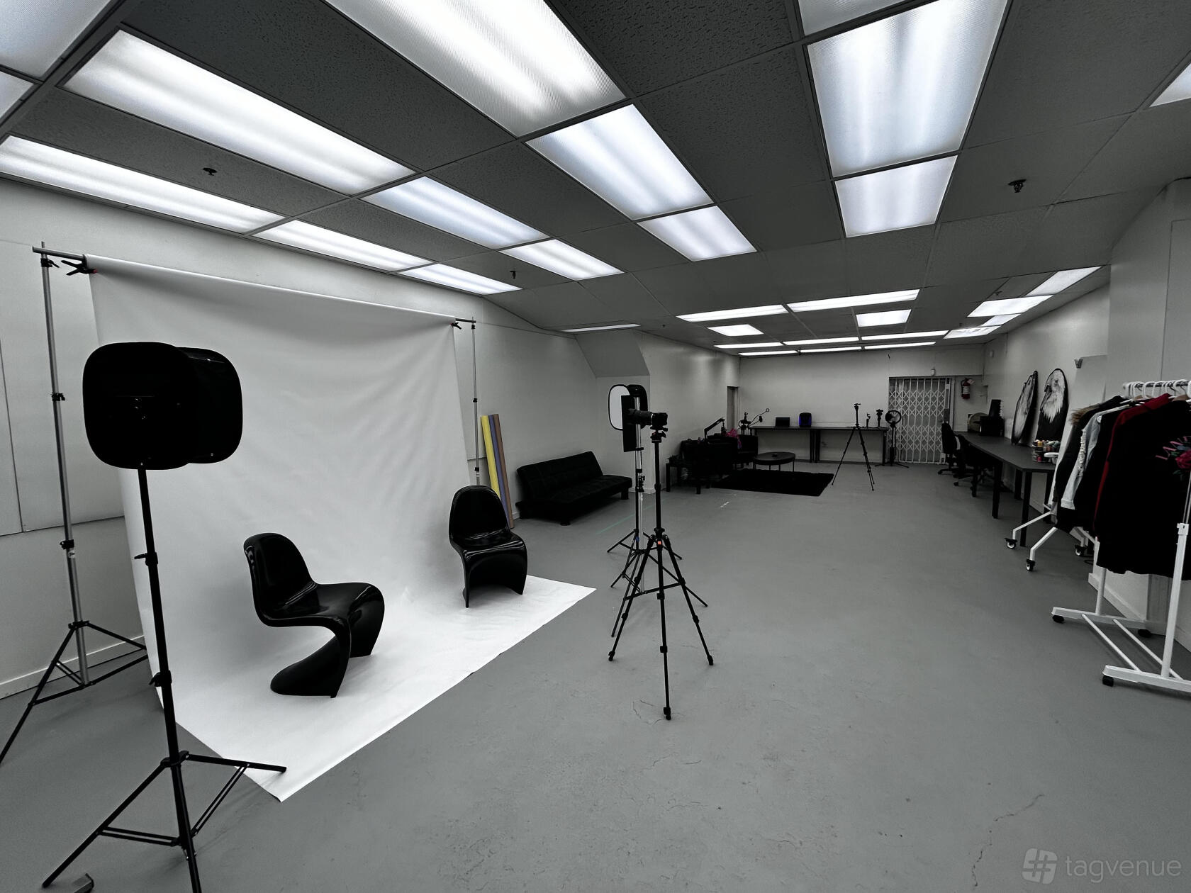 A film studio with seamless white backdrop, black chairs, softbox lighting, and open workspace at Land Back Labs.