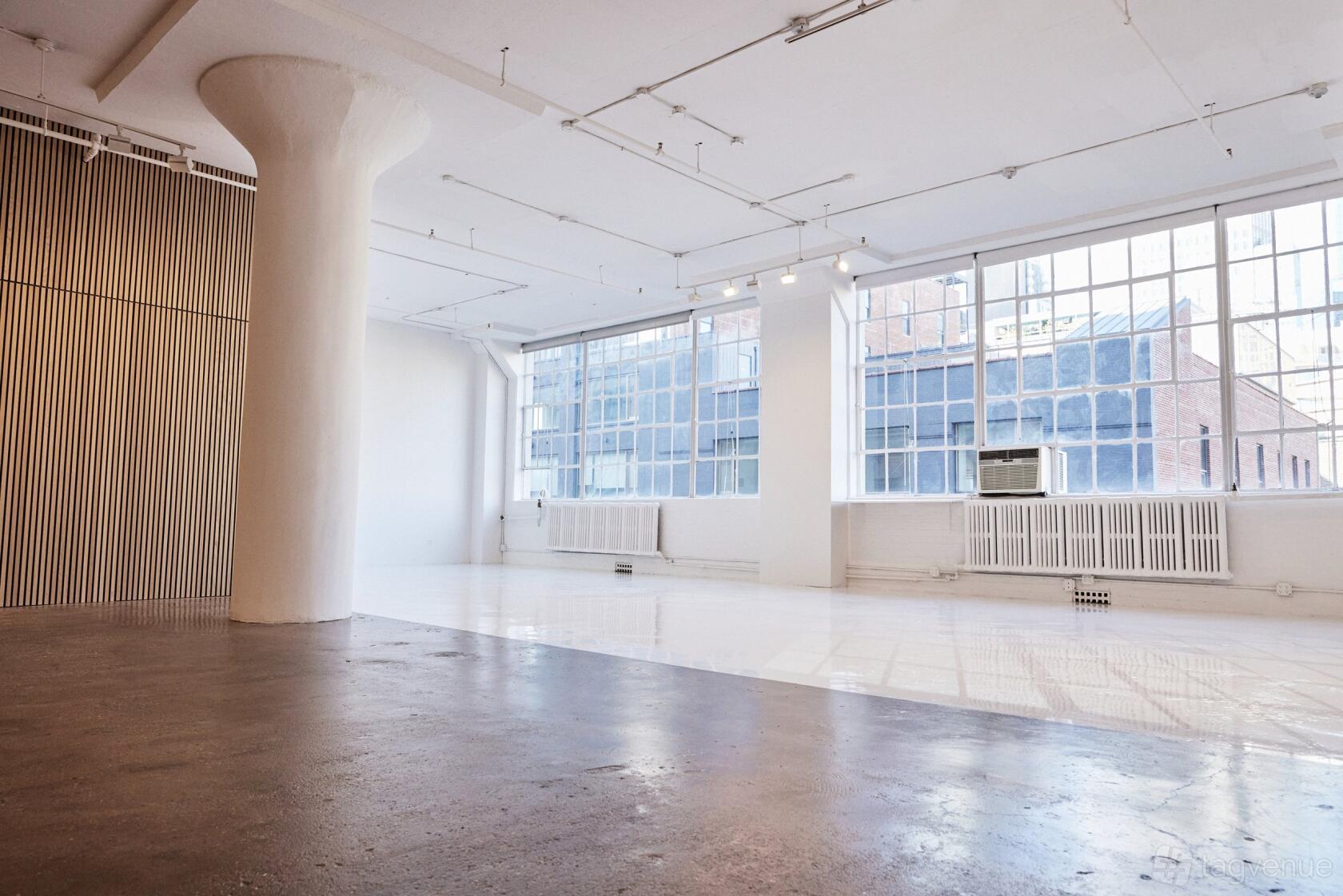 An event venue with large industrial windows, white walls, exposed pipes, and polished floors at EDEN STUDIO NYC.