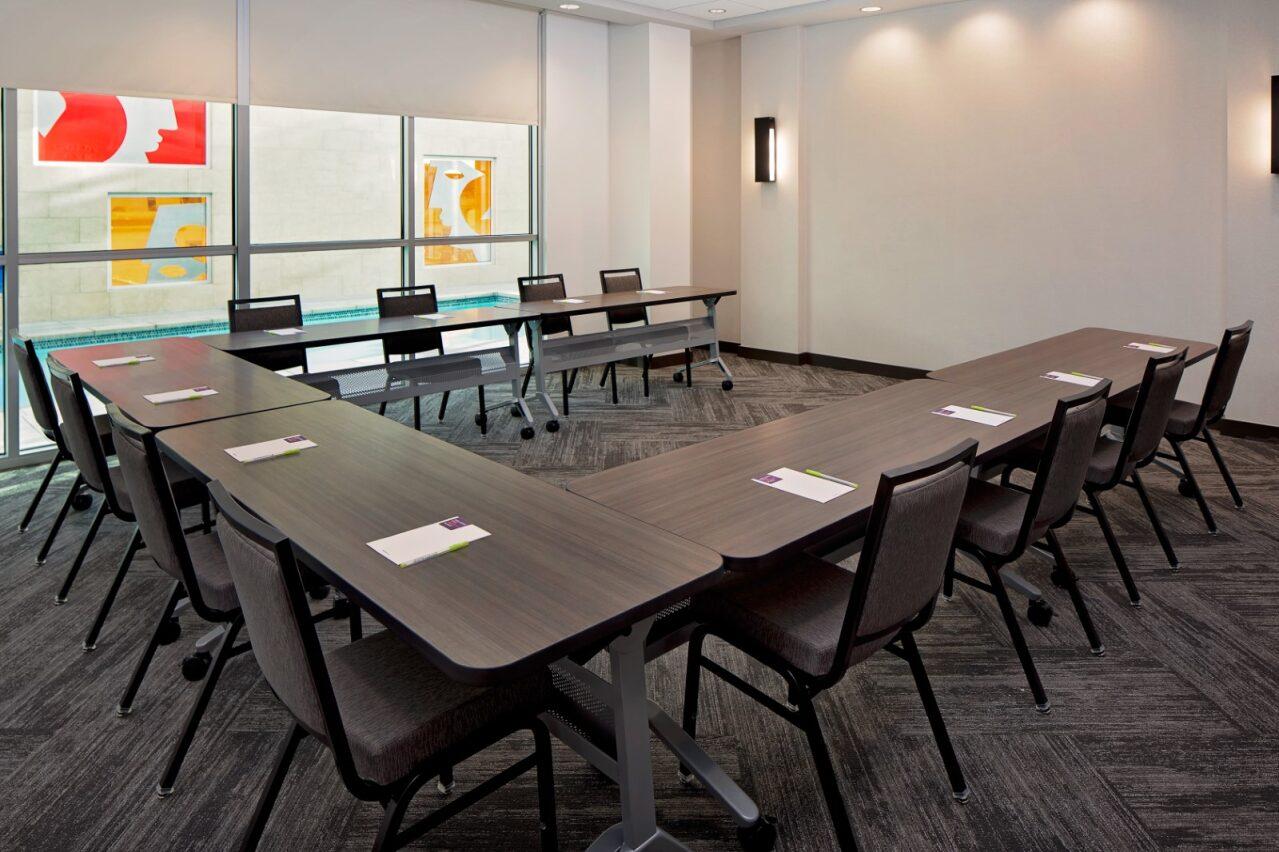 A meeting room with U-shaped tables, notepads on each seat, and carpeted flooring at Hyatt Place Glendale/Los Angeles.