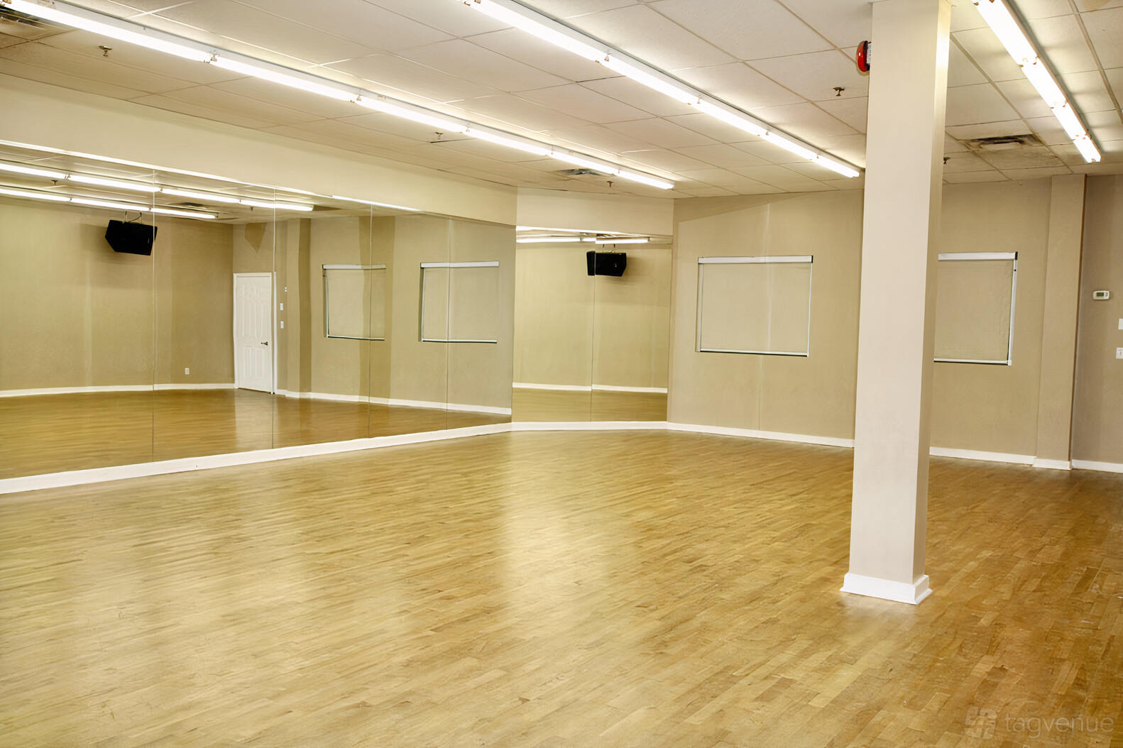 A dance studio with mirrored walls, wood flooring, and ceiling strip lighting at ViBE Dance Studio.