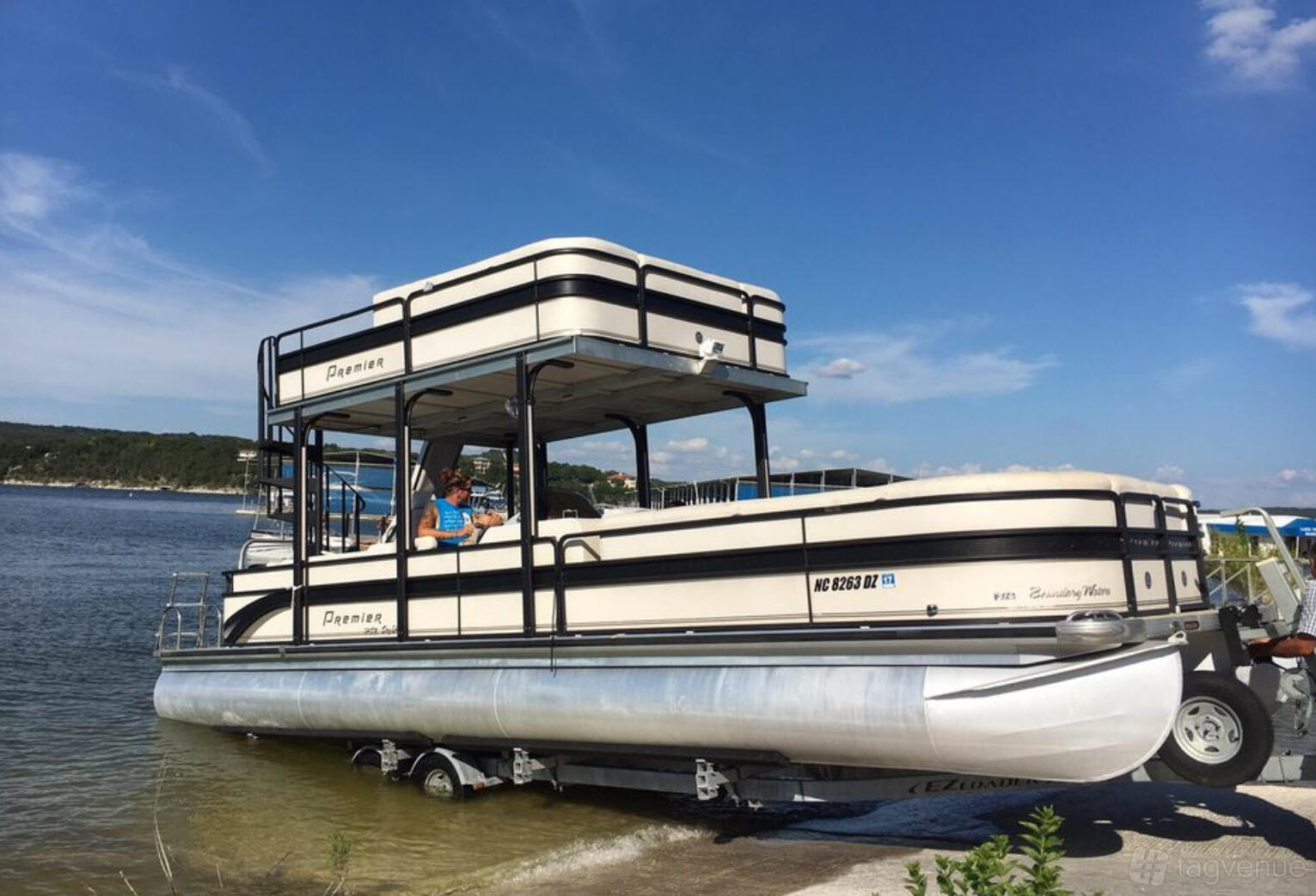 A double decker party boat with shaded upper and lower seating areas docked by the water at Austin's Boat Tours.