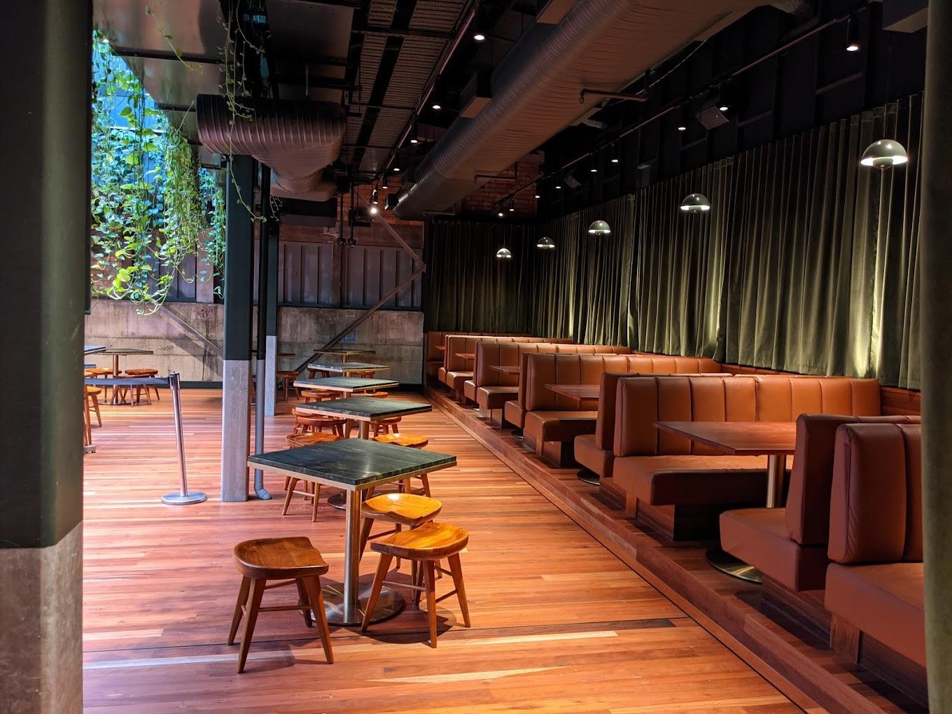 A dining room with brown leather booths, wooden floors, and dark marble tables at The Sound Garden.