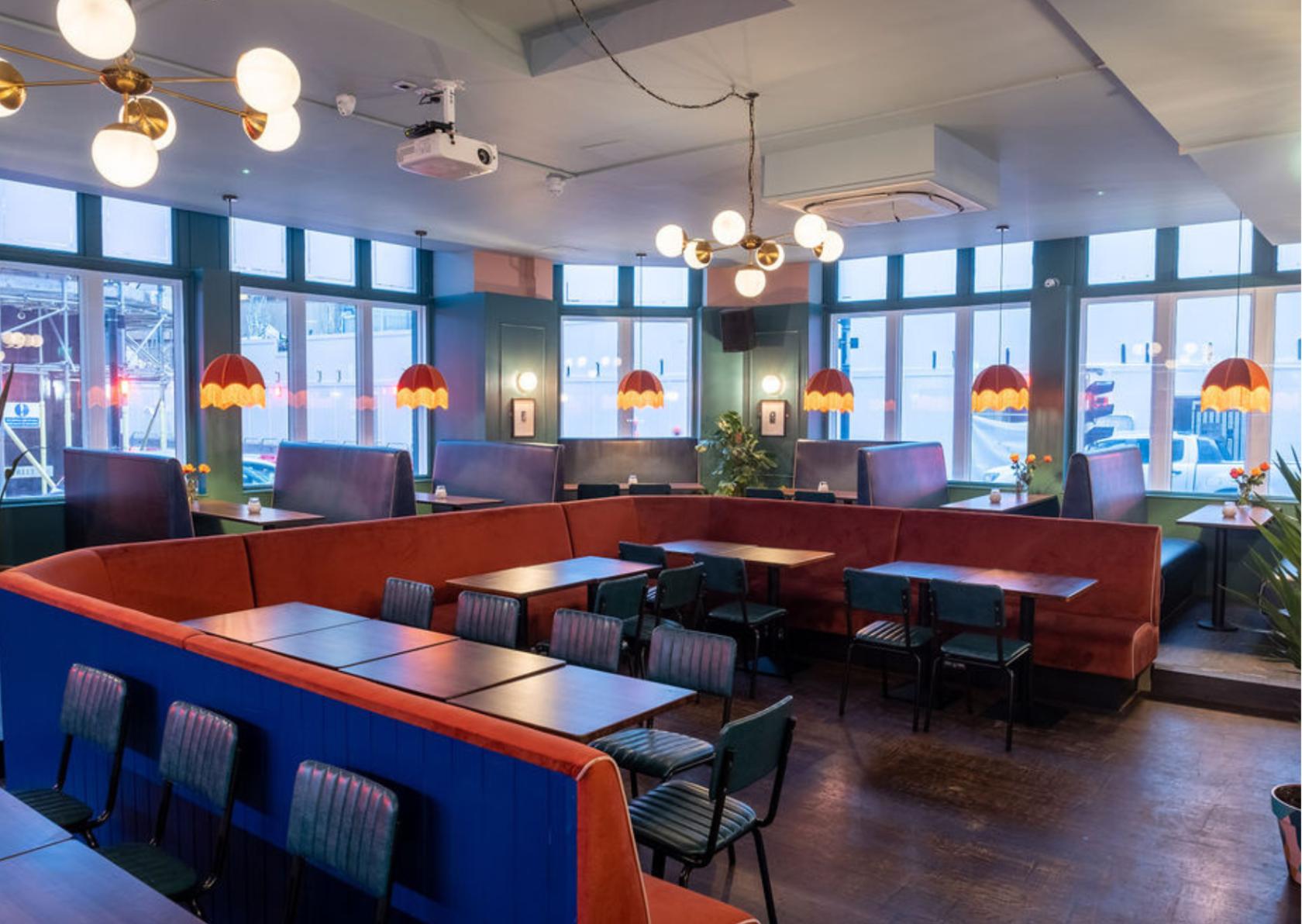 A karaoke lounge with booth seating, colorful pendant lamps, and large windows at Star by Liverpool Street.