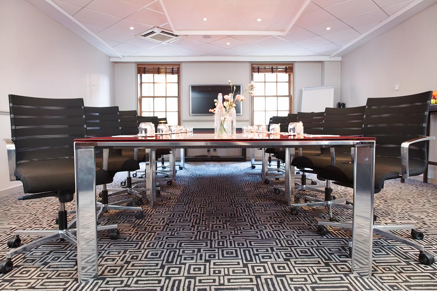 A hotel boardroom with a geometric carpet, black leather chairs, and a central glass-topped table at Radisson Blu Hotel, Edinburgh City.