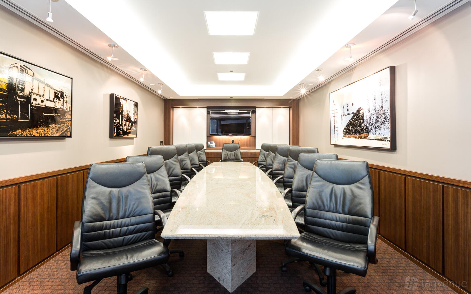 A boardroom with a long marble conference table, black leather chairs, and framed artwork at Servcorp - The Loop, Chicago.