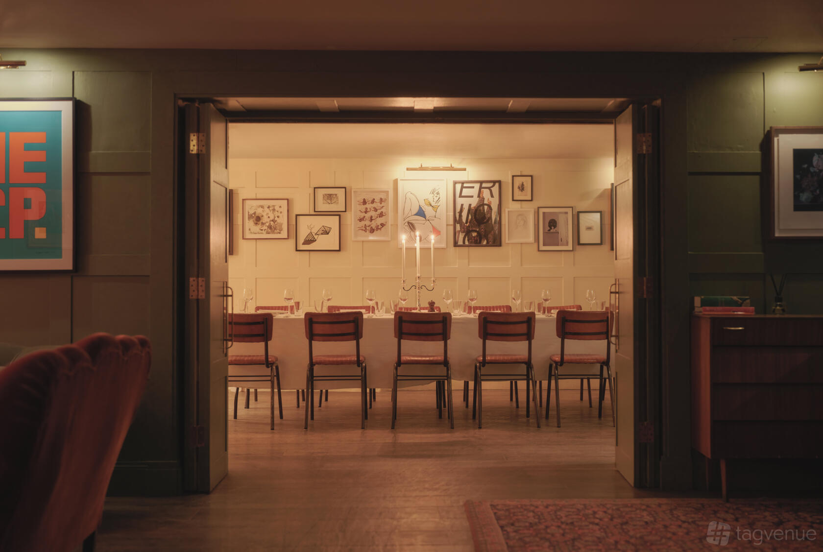 An event space with a long dining table, wooden chairs, candlelight, and framed art on the walls at High Road House.