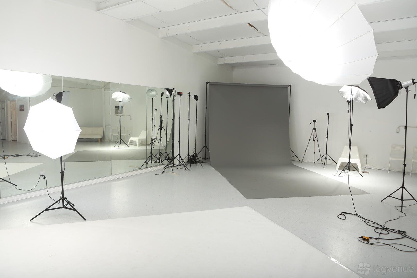 A photo studio with large softbox lights, a gray backdrop, and wall-length mirrors at Stunner Studios.
