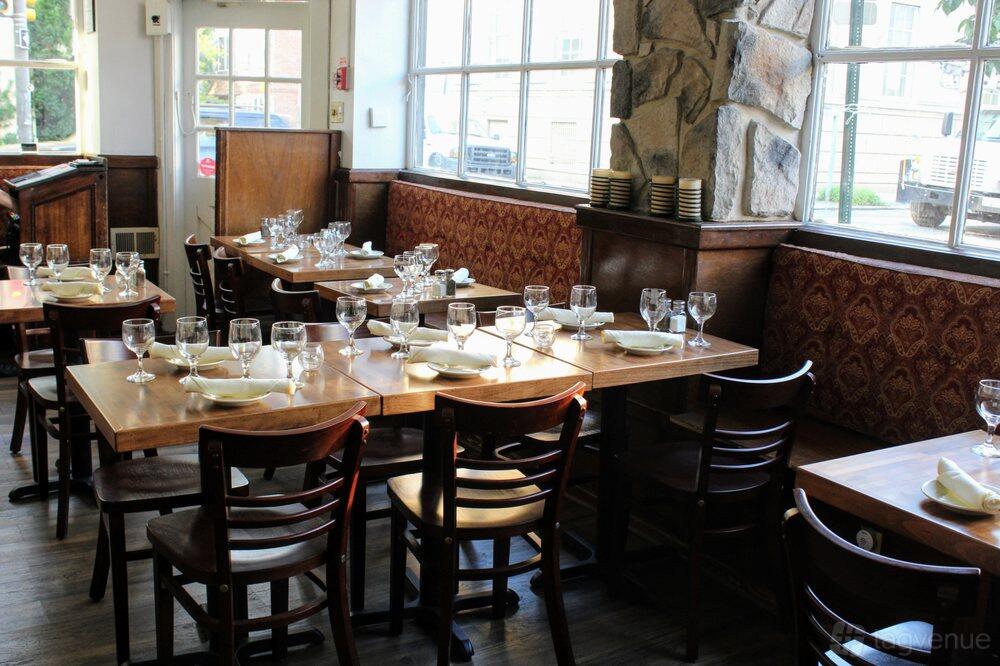 A restaurant with wooden tables, upholstered bench seating, and large windows at Bistro La Baia.