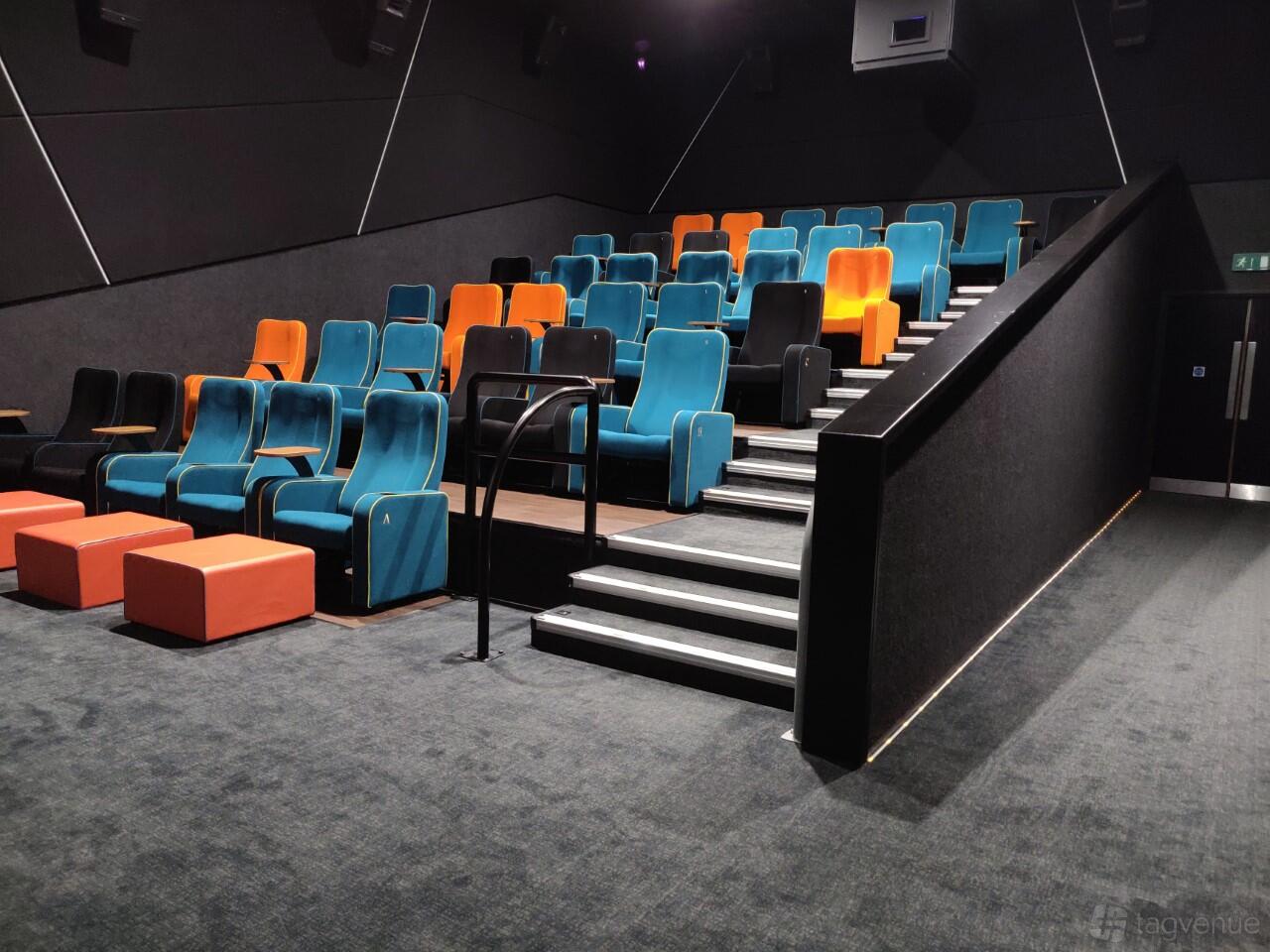 A cinema auditorium with tiered blue and orange seats and aisle lighting at The Light Cinema - Bradford.