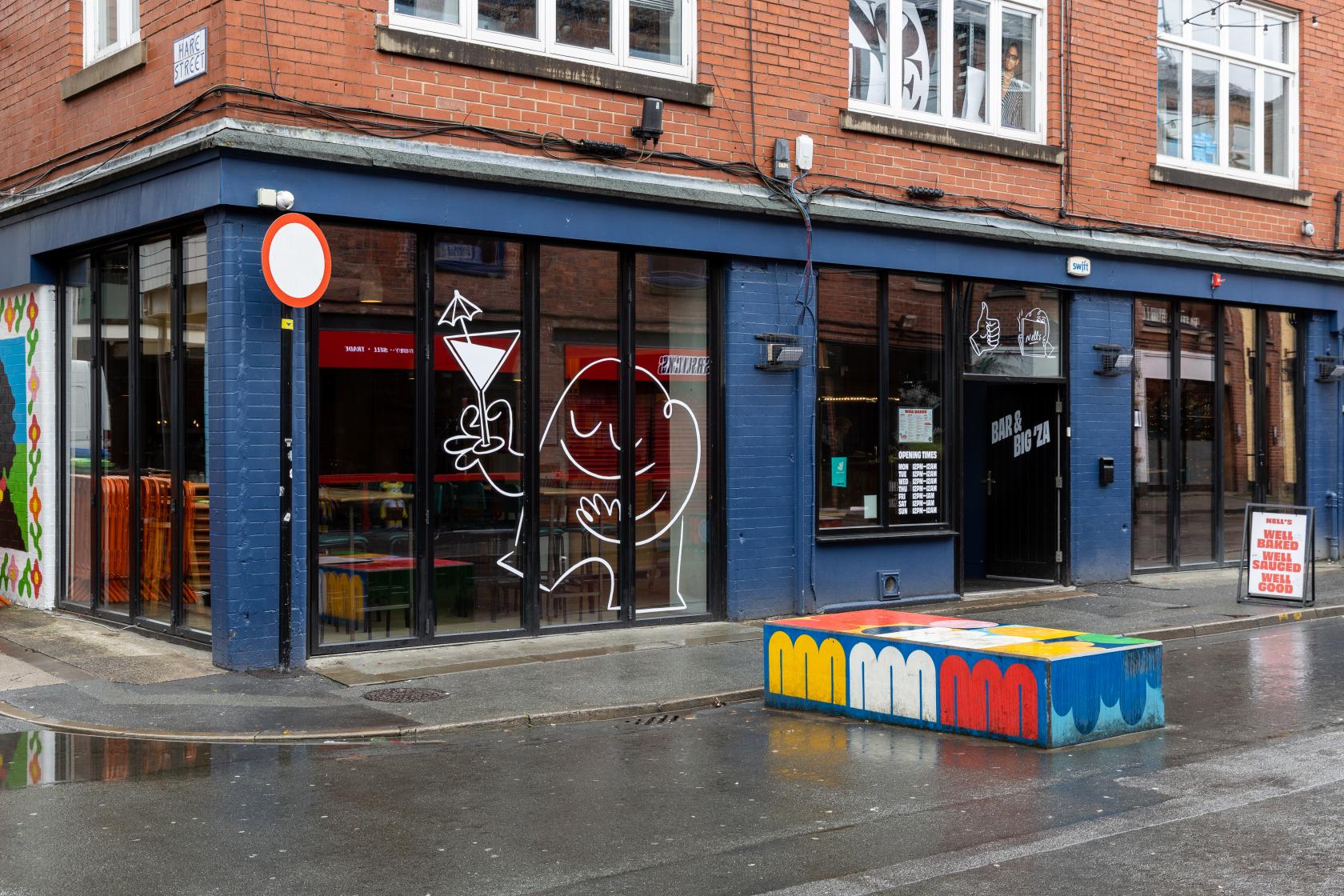 A pub with large street-facing windows, brick exterior, and playful window art at Common.