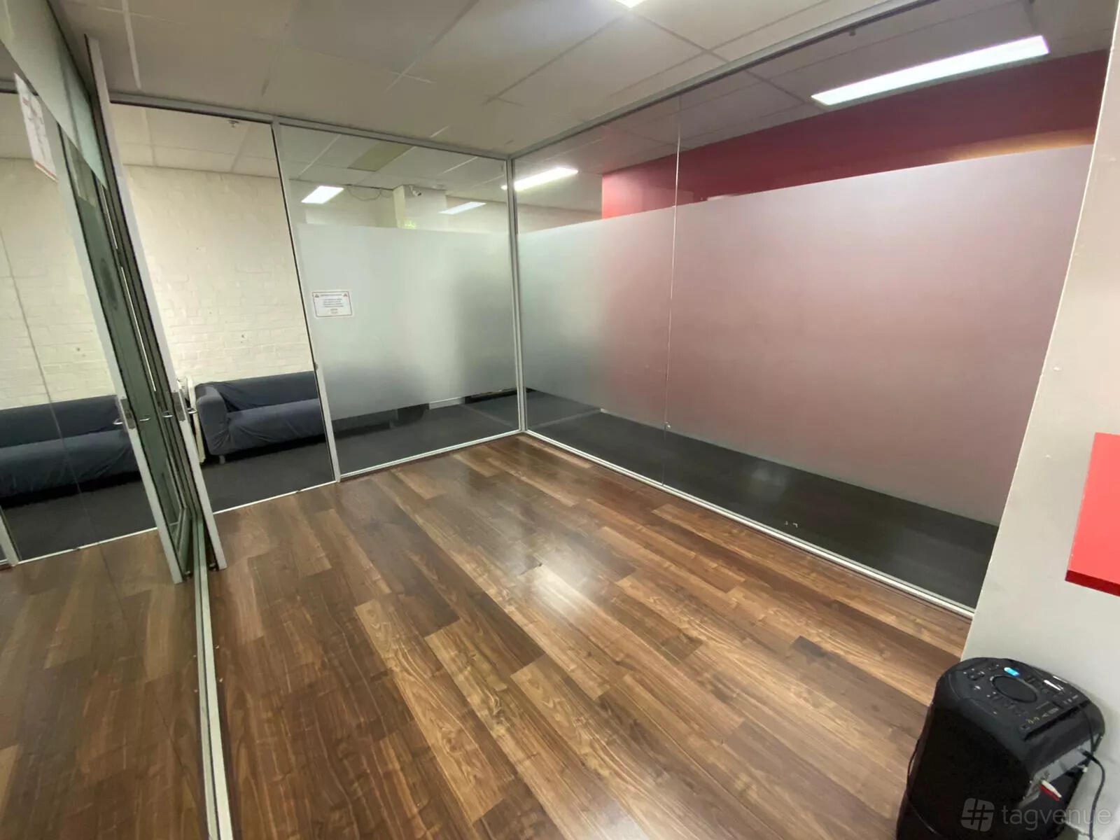 A dance studio with wooden floors, glass walls, and frosted paneling at Latin Dance Australia.