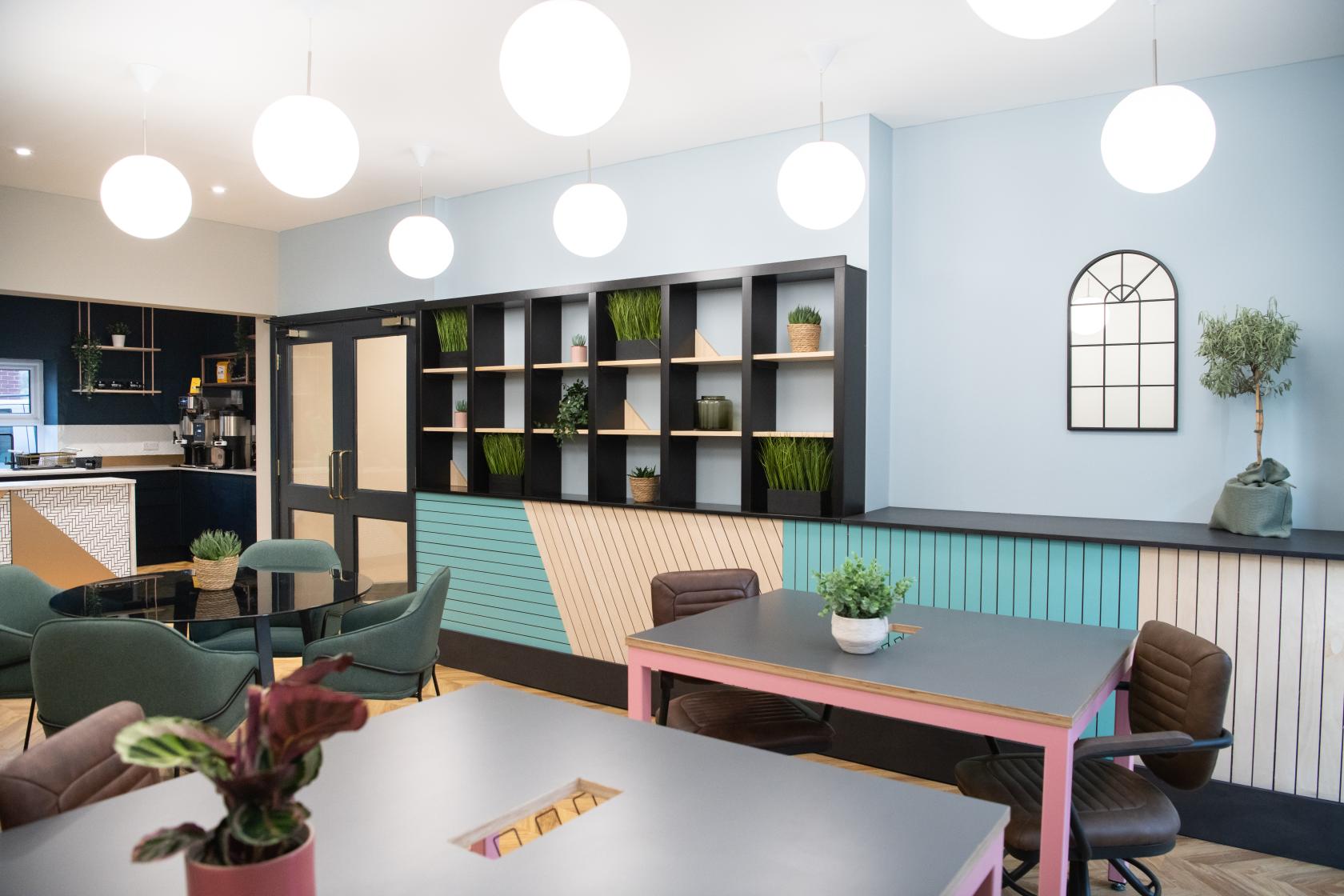 A coworking space with round pendant lights, indoor plants, and modern tables at Wizu Workspace - Harrogate - Royal House.
