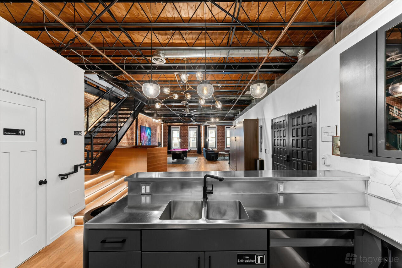 An event space in a hotel with exposed brick walls, industrial lighting, and stainless steel counters at Hotel Residential of Denver.