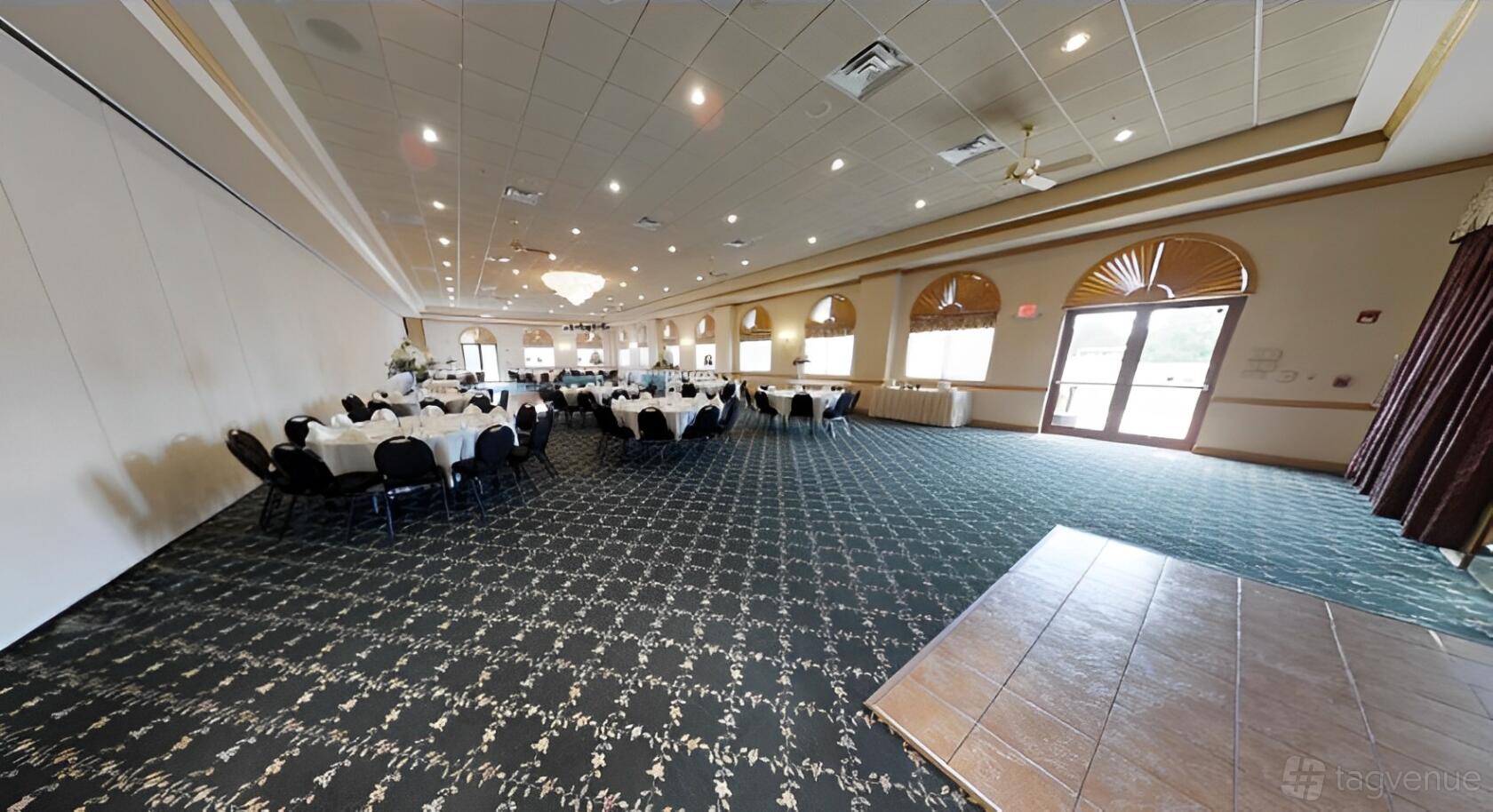 An event venue with round tables dressed in white linens, arched windows, and patterned carpet at Jennifer's Garden.