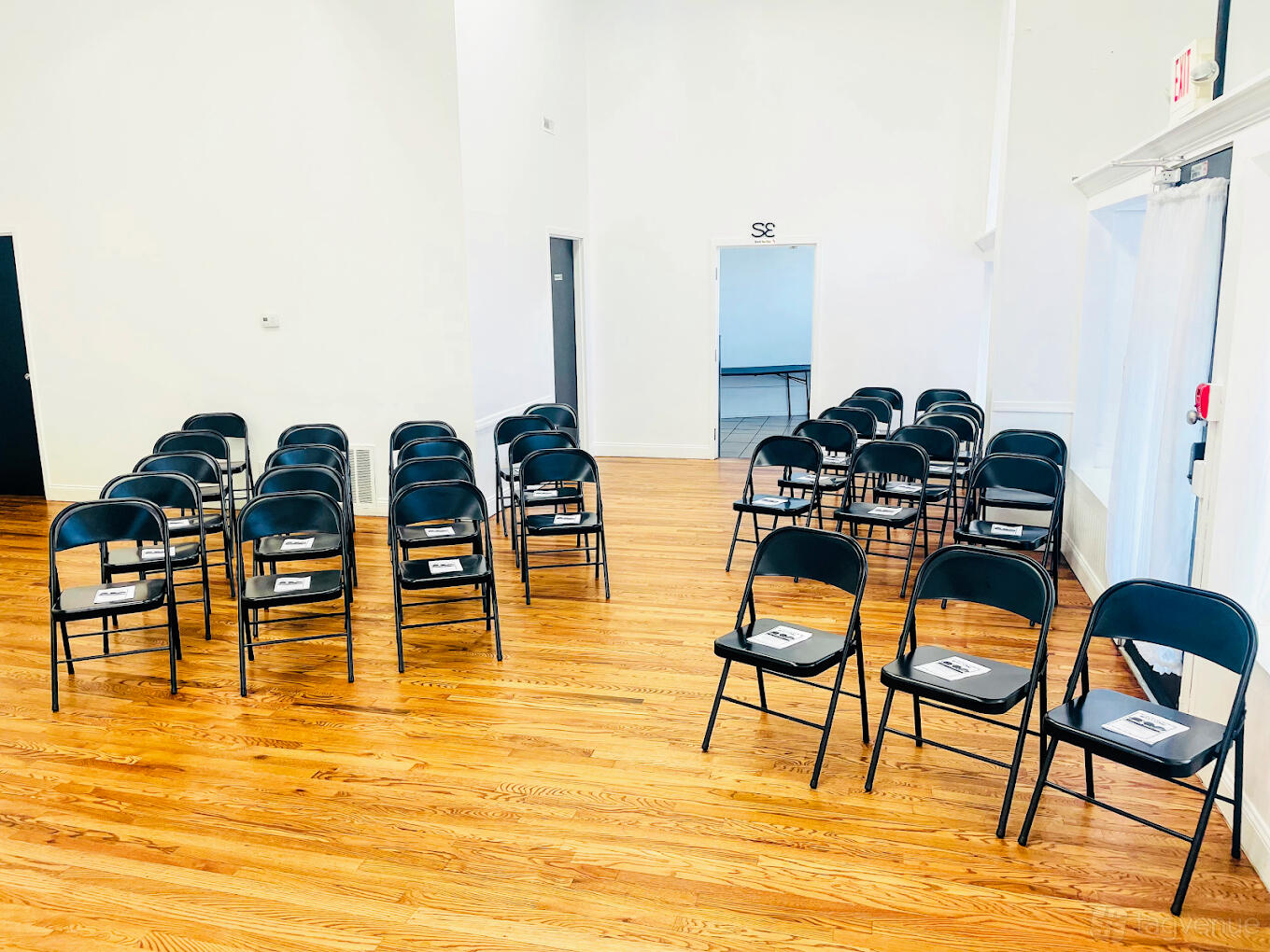 An event venue with rows of black folding chairs on polished hardwood floors at Sorella's Events, LLC.