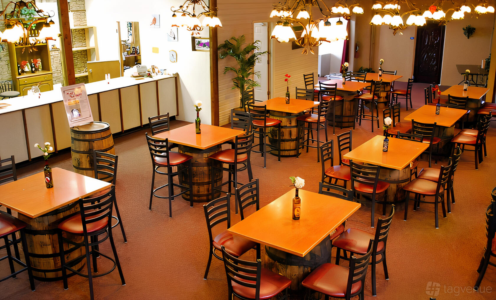 A bar with square wooden tables, barrel bases, and floral centerpieces in the Party Room at Cardinal Hollow Winery.