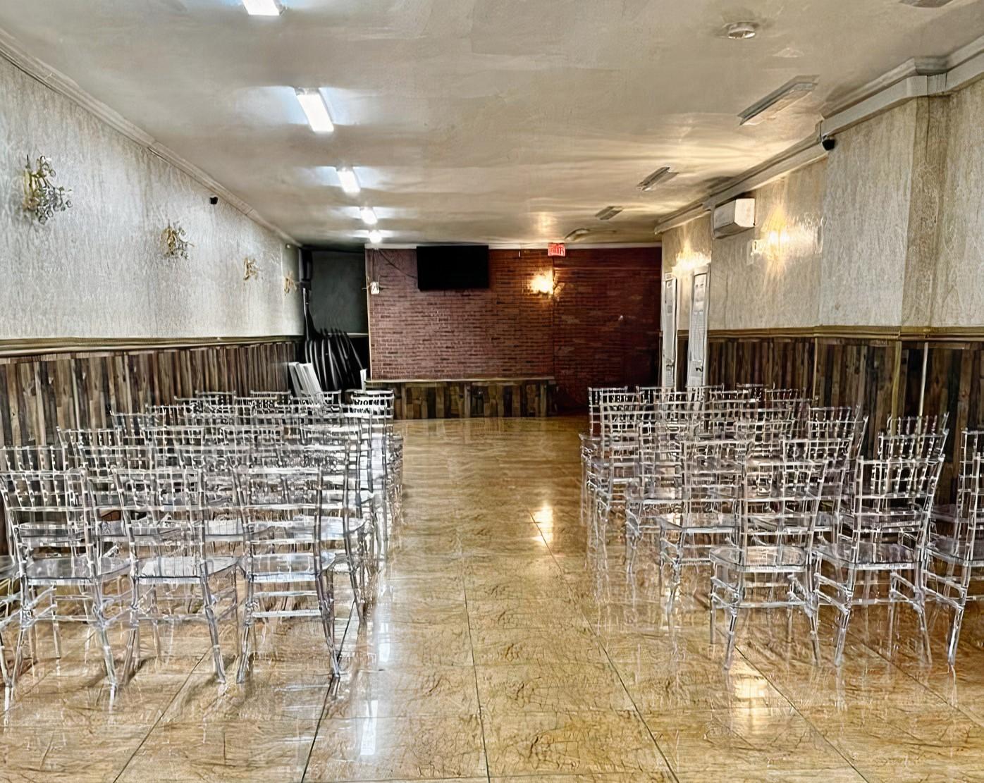 An event venue with clear acrylic chairs, paneled walls, and a brick accent wall at The Aurum.