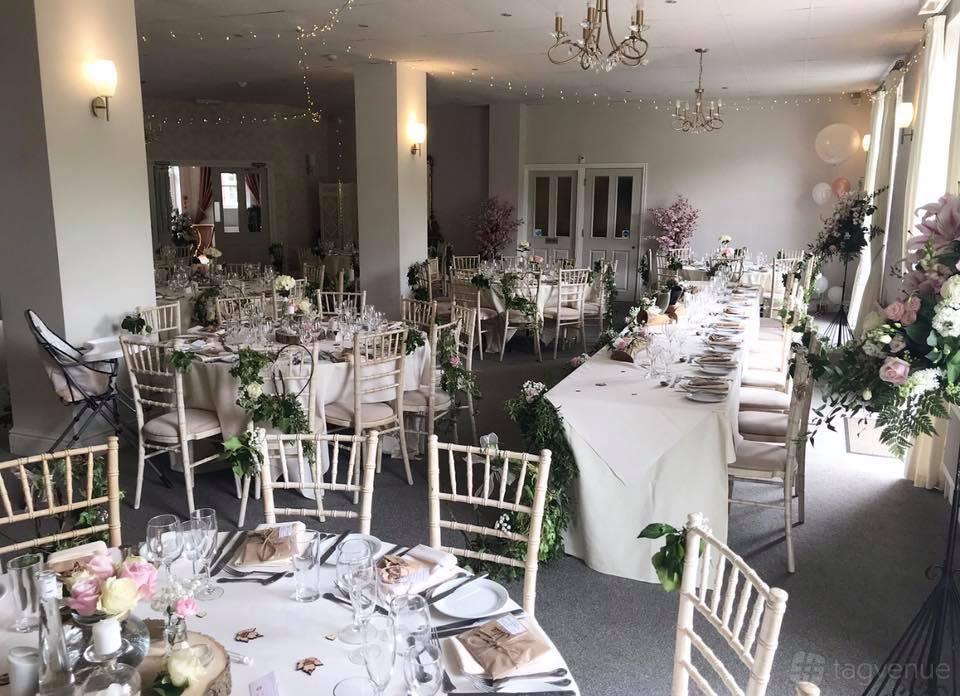 A hotel dining room with white tablecloths, floral centerpieces, and Chiavari chairs at Fox & Hounds.