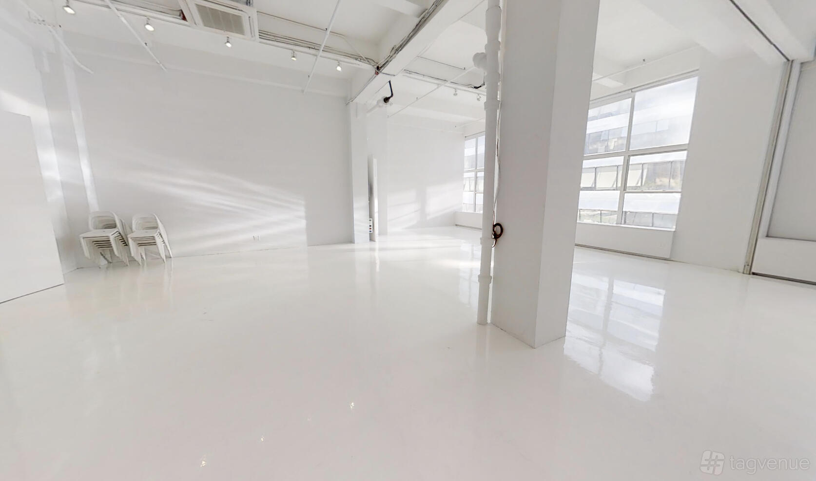 An event venue with white polished floors, high ceilings, and large windows at Location 05.