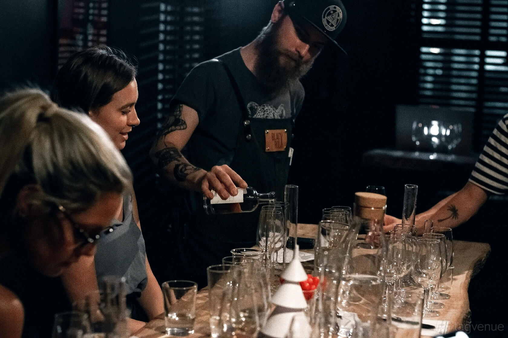 A bar with a wooden counter, various empty glasses, and a bartender pouring drinks at Black Rock Bar.
