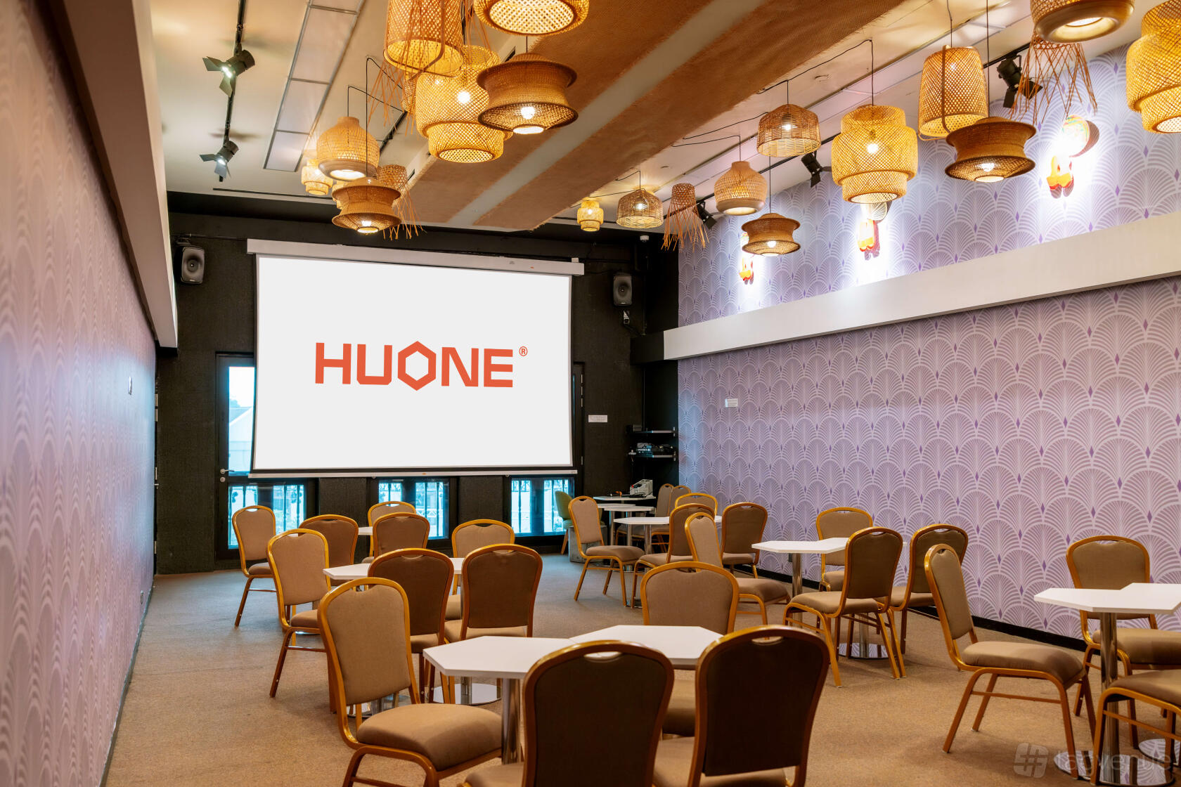 An event venue with woven pendant lighting, purple patterned walls, and round tables with chairs at HUONE Singapore.