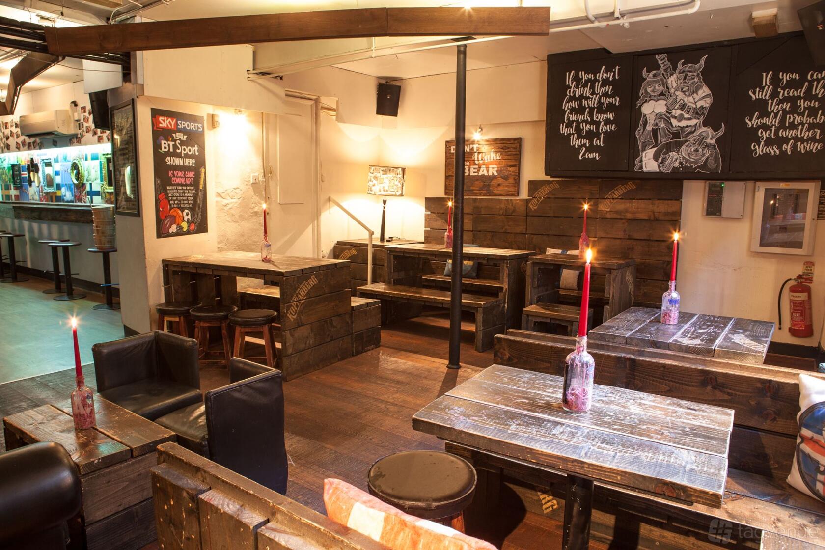 An event space in a bar with rustic wooden tables, bench seating, and wall art at Nordic Bar.