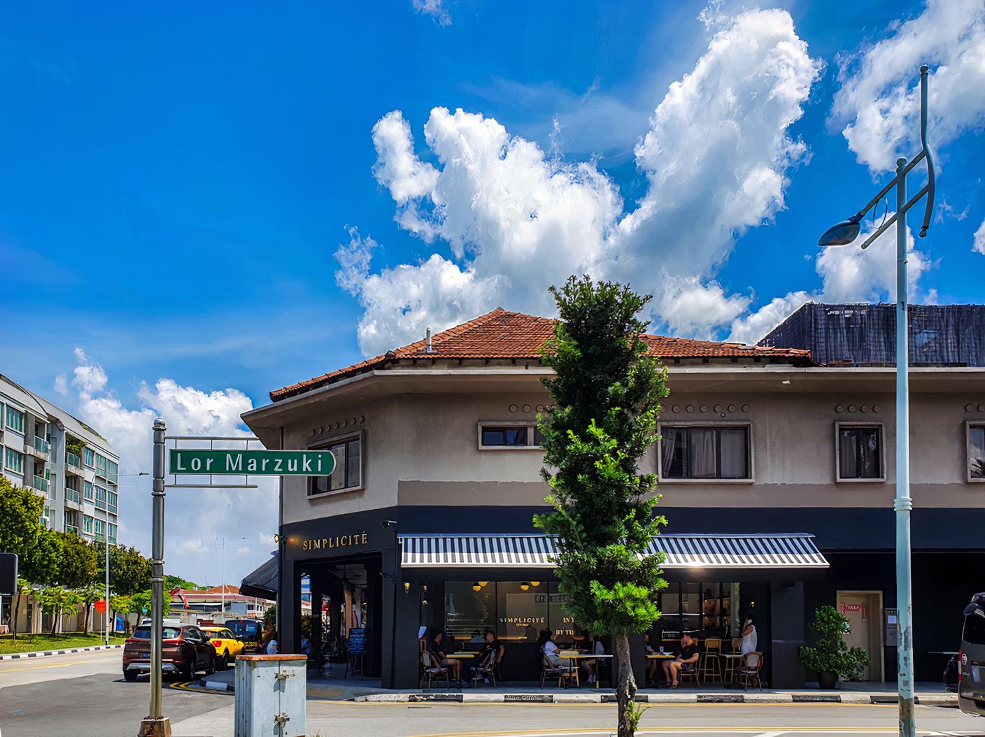 A café with outdoor seating beneath a striped awning and large street-facing windows at Simplicité