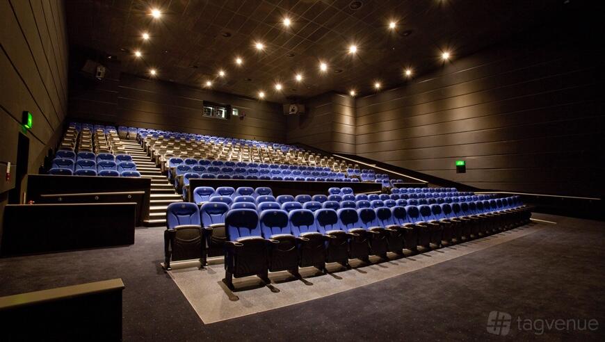 A screening room with tiered rows of blue seats and dim ceiling lights at ODEON Trafford Centre.