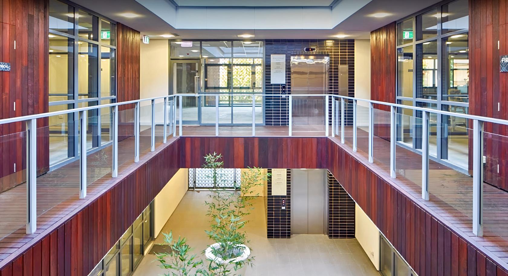 A versatile event space with an open atrium, glass walls, and wood panel accents at Subi Space.