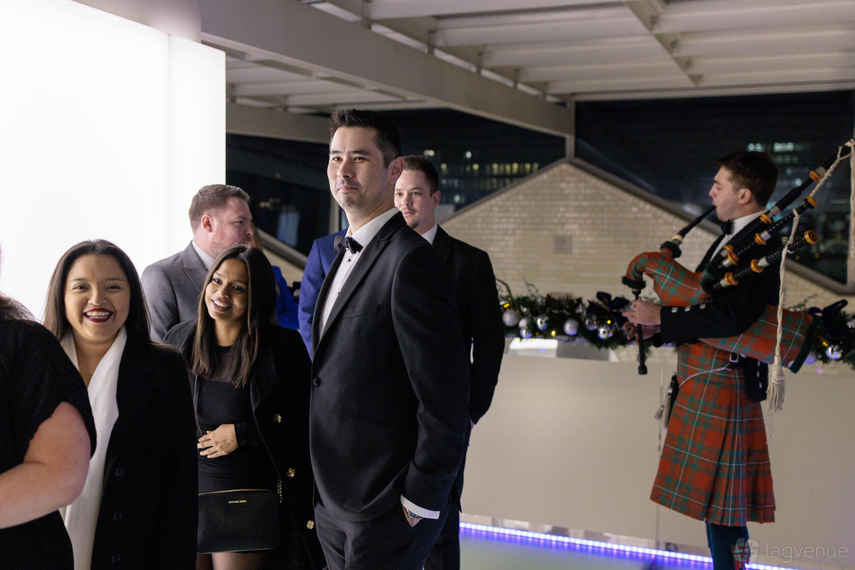 A rooftop event venue with white walls, garland decorations, and a bagpiper performing at 30 Euston Square.