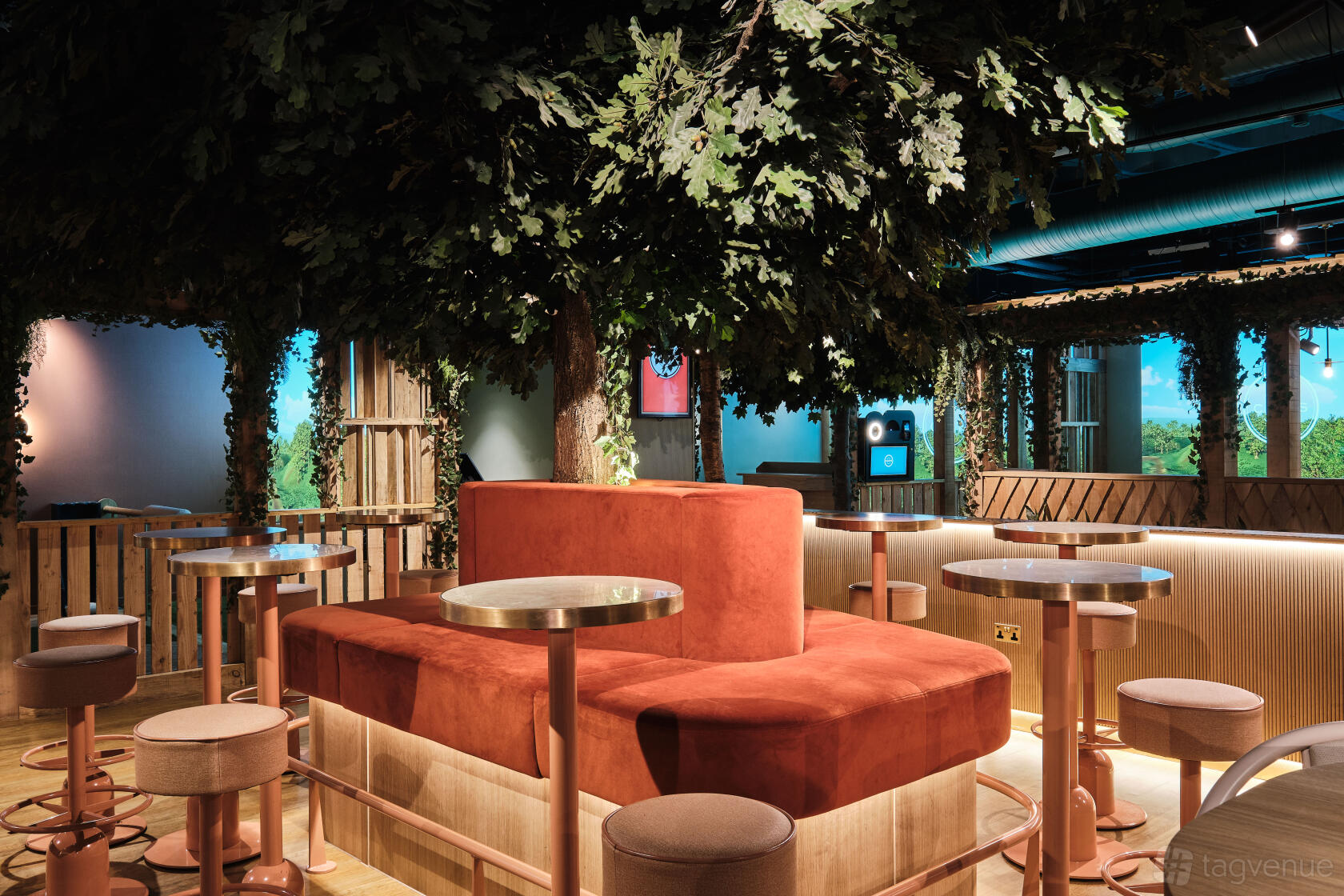 A cocktail bar with plush seating, round tables, and tree-inspired décor at Clays City.