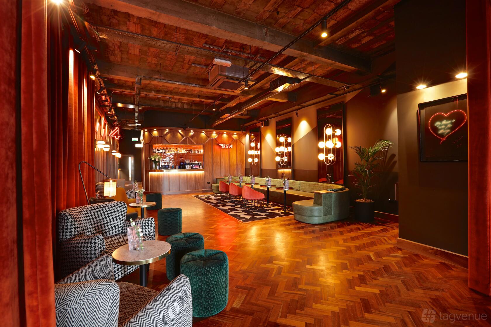 A cinema lounge with velvet armchairs, parquet flooring, and warm pendant lighting at Everyman Crystal Palace.