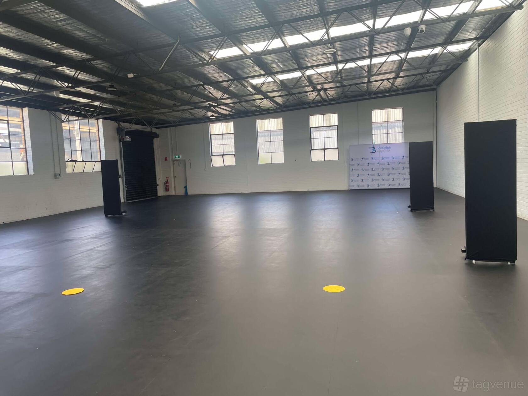 A dance studio with high ceilings, large industrial windows, and a spacious open floor at Bentleigh Calisthenics Studios.